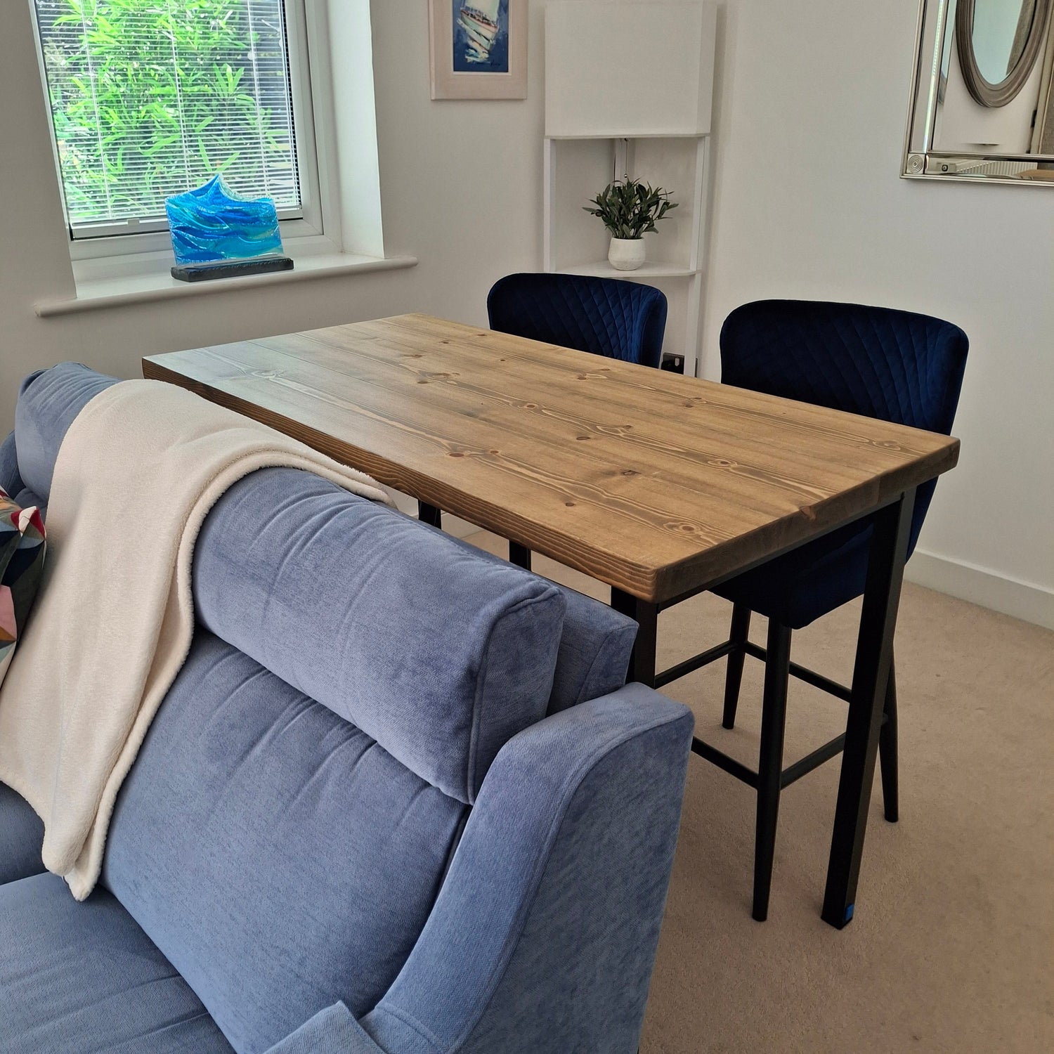 Room interior with a wooden table, chairs, and a sofa near a window.