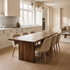 A minimalist wooden dining table with a thick rectangular top and two blocky legs, shown in a warm, neutral-toned room with beige walls and floor.
