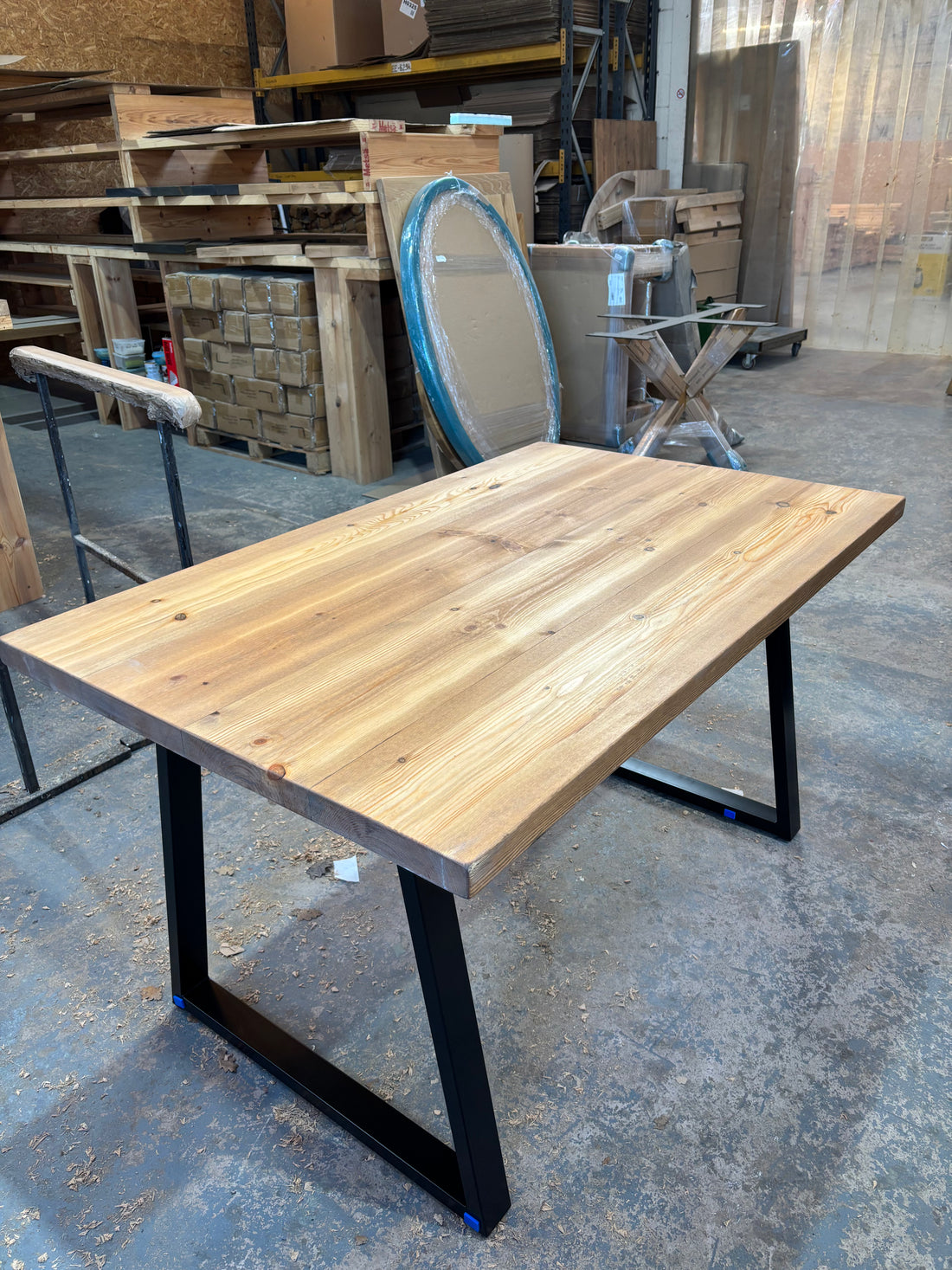 Wooden table with black metal legs in a warehouse setting