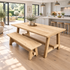 A light natural wood dining table with matching bench in a bright, modern kitchen and patio setting.