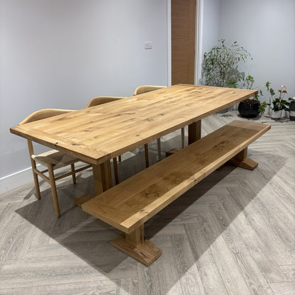 Wooden dining table with chairs and a bench in a room with light gray walls and flooring.