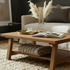 Wooden coffee table with a vase of pampas grass, books, and a cup in a living room setting.
